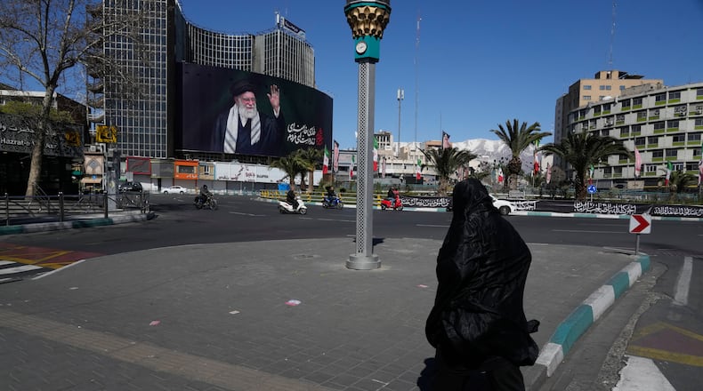 A woman crosses almost deserted square with a billboard at rear showing a portrait of the late Iranian Supreme Leader Ayatollah Ali Khamenei, who was killed in the U.S.–Israeli military campaign, in Tehran, Iran, Tuesday, March 3, 2026. (AP Photo/Vahid Salemi)