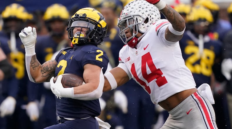 Michigan running back Blake Corum (2) is chased by Ohio State safety Ronnie Hickman (14) during the second half of an NCAA college football game, Saturday, Nov. 27, 2021, in Ann Arbor, Mich. (AP Photo/Carlos Osorio)