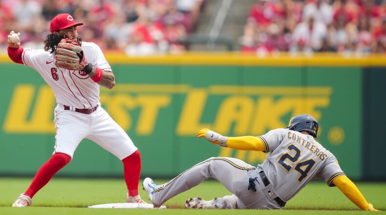 Cincinnati Reds' Jonathan India, left, throws to first base after forcing out Milwaukee Brewers' William Contreras, right, at second base during the first inning of a baseball game in Cincinnati, Sunday, July 16, 2023. (AP Photo/Aaron Doster)
