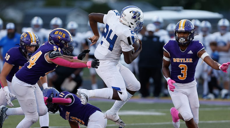 Xenia's Deaute White leaps over a Butler player as he carries the ball. BILL LACKEY/STAFF