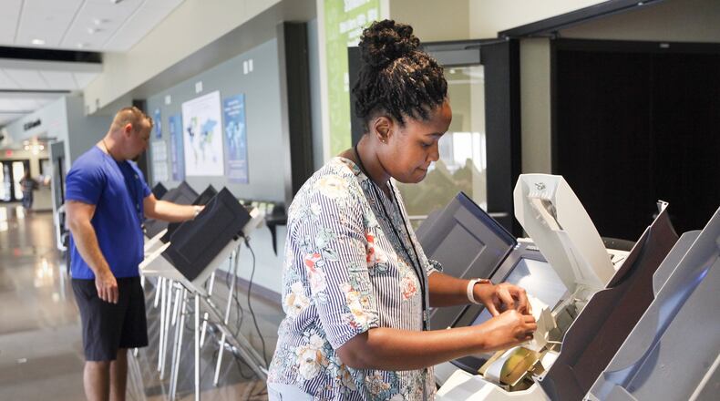 Montgomery County elections workers Lakesia McLemore, right, and Brandon Izor set up polling machines Monday at the Christian Life Center where voters from four Butler Twp. precincts will cast ballots Tuesday. CHRIS STEWART / STAFF