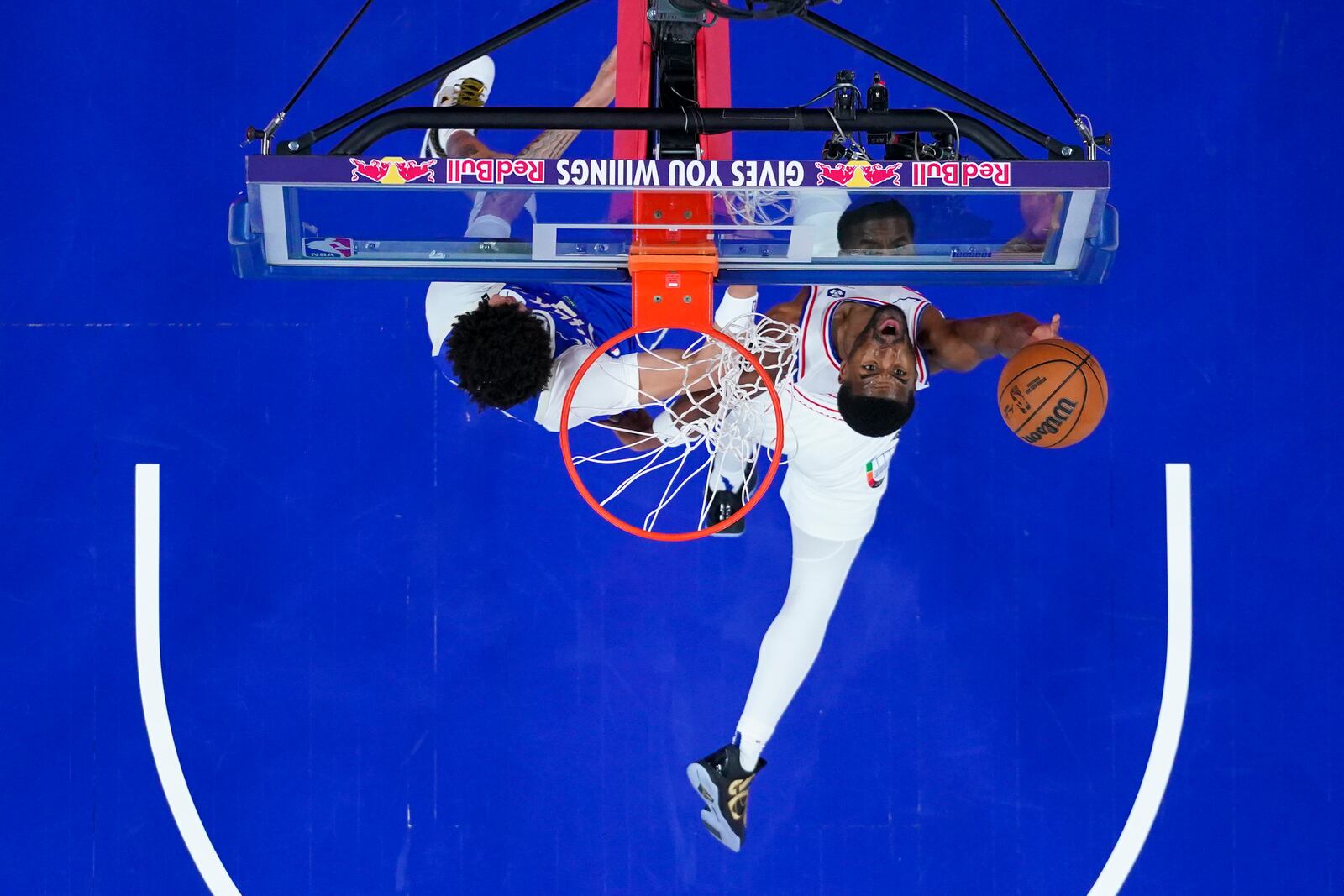 Philadelphia 76ers' Jared Butler, right, goes up for the shot against Milwaukee Bucks' Ryan Rollins, left, during the first half of an NBA basketball game, Thursday, April 3, 2025, in Philadelphia. (AP Photo/Chris Szagola)
