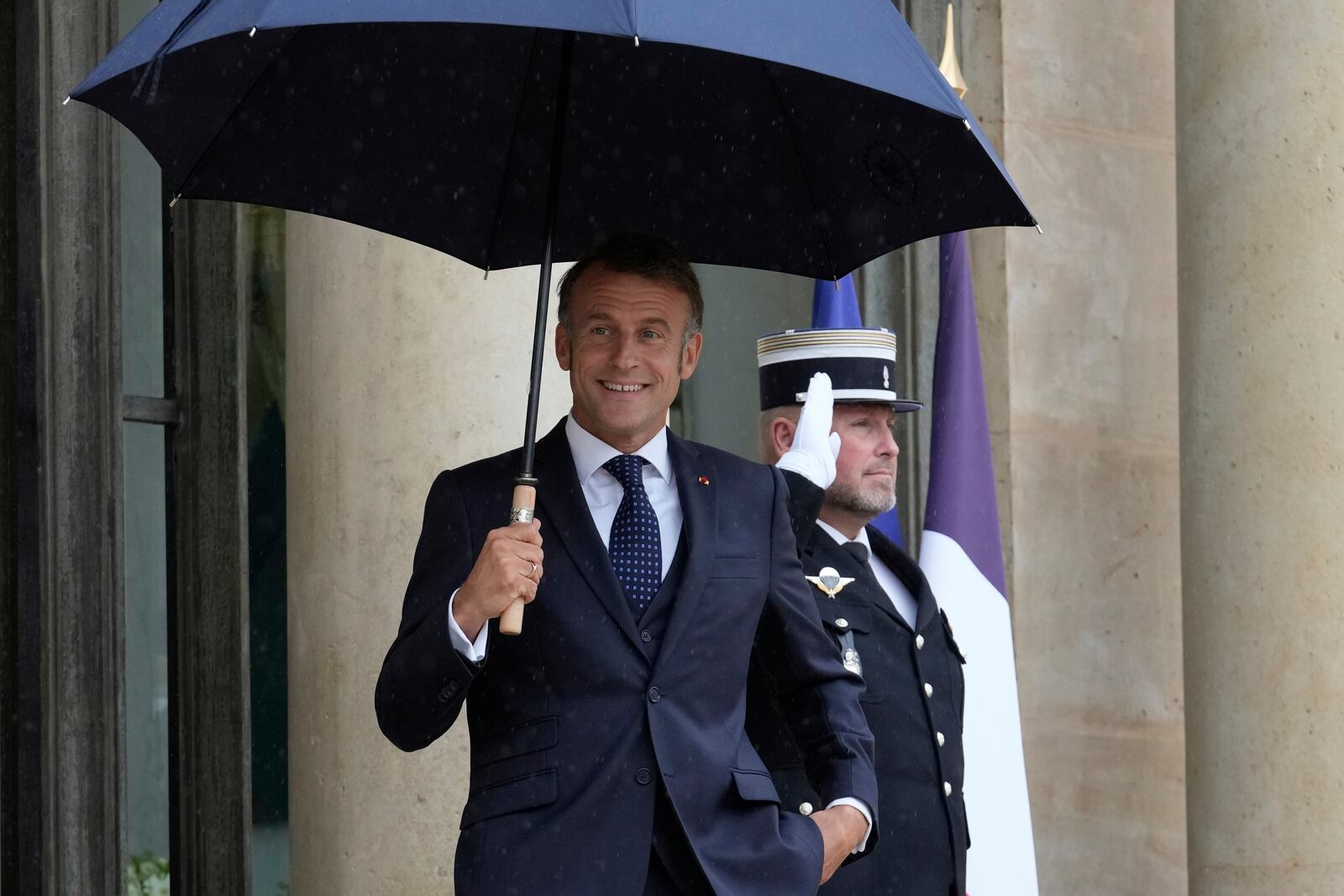 French President Emmanuel Macron uses an umbrella as he waits for Lebanese Prime Minister Nawaf Salam Thursday, July 24, 2025 at the Elysee Palace in Paris. (AP Photo/Michel Euler)