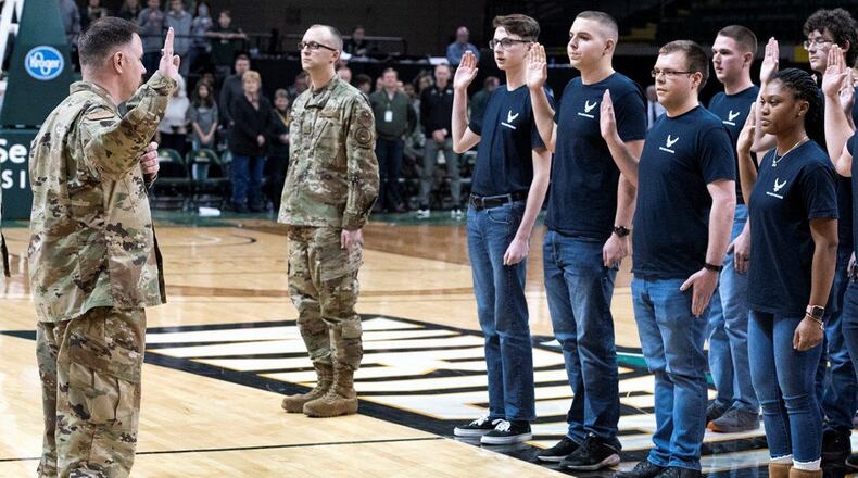 Col. Michael Phillips, 88th Air Base Wing vice commander, administers the oath of enlistment to 19 members of the delayed enlistment program during the Wright State University Men’s Basketball Military Appreciation Night at the Nutter Center Jan. 18. Members of the military also presented the game ball, sung the national anthem and presented the colors during the pregame ceremonies. (U.S. Air Force photo/Wesley Farnsworth)