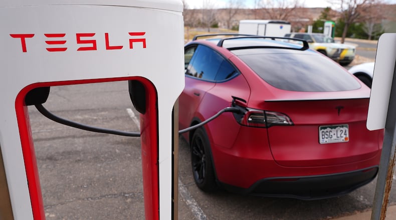 A motorist sits in a Tesla Model 3 at a Tesla charging station Friday, March 13, 2026, in Lakewood, Colo., in Denver. (AP Photo/David Zalubowski)
