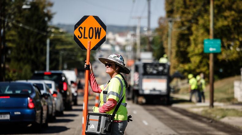 Dana Combs from Jurgensen Asphalt directs traffic on Wayne Avenue on Tuesday October 3, 2023. Crews started repaving a section of Wayne Avenue near the Esther Price store on Tuesday October 3, 2023. JIM NOELKER/STAFF