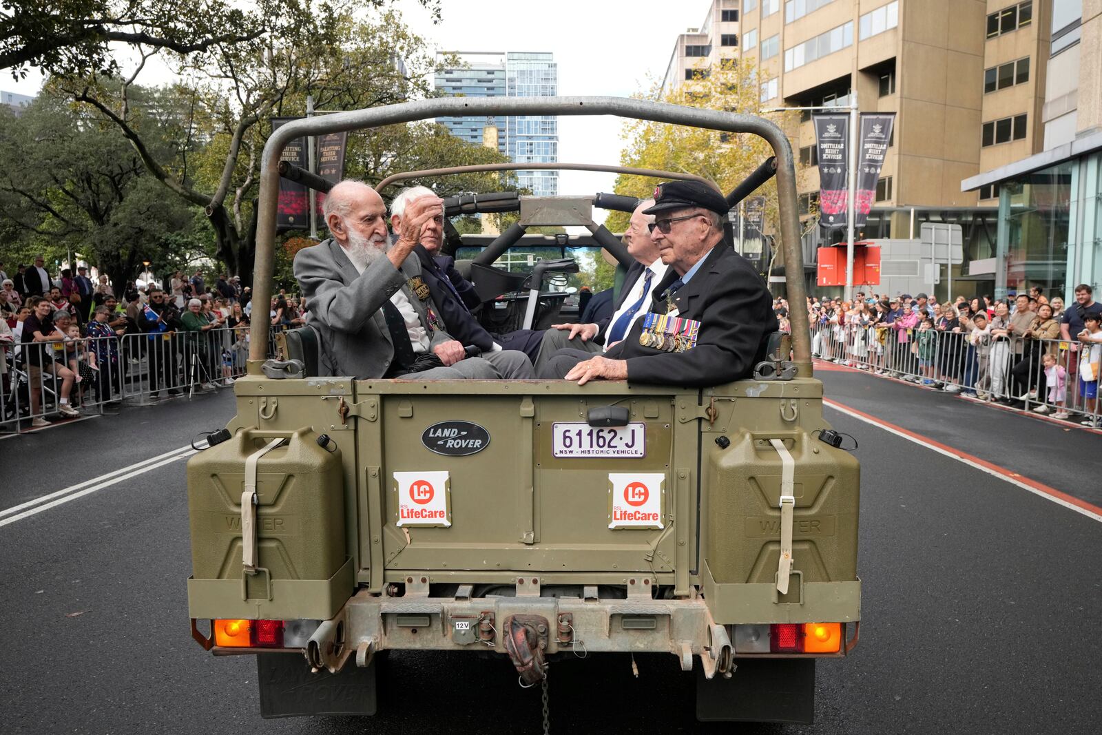 Veterans ride in the back of an army truck past thousands of people lining the street to pay tribute to their war dead during the Anzac Day parade in Sydney, Australia, Friday, April 25, 2025. (AP Photo/Rick Rycroft)