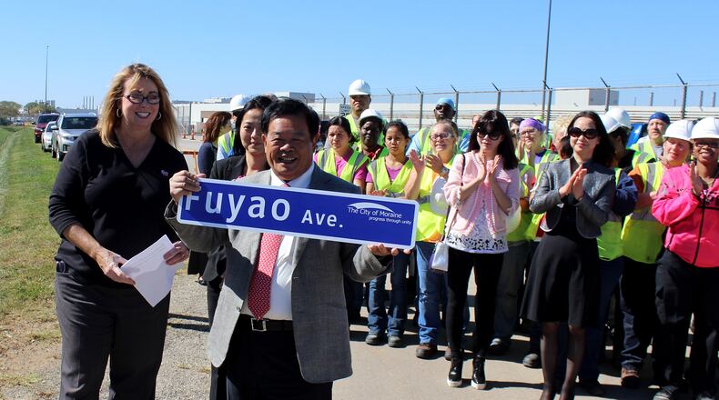 Moraine Mayor Elaine Allison and Fuyao Chairman Cao Dewang display the Fuayo Avenue street sign during dedication cerimonies in front of factory workers.