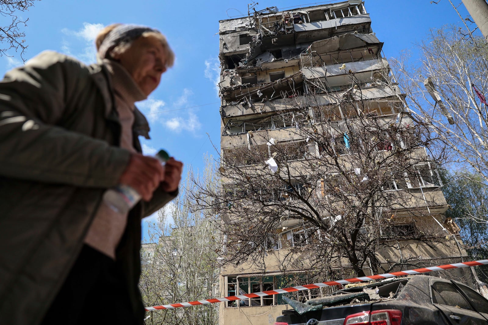 A woman walks in front of a multi-storey building damaged by a Russian strike on a residential neighbourhood in Zaporizhzhia, Ukraine, on Tuesday, April 22, 2025. (AP Photo/Kateryna Klochko)
