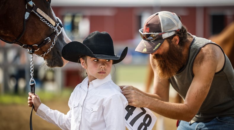 Zach Smith, from New Lebanon puts a competition number on his daughter, Kara McNutt, 10, before the 4-H Horse Show at the Montgomery County Fair Tuesday morning July 11, 2023. JIM NOELKER/STAFF