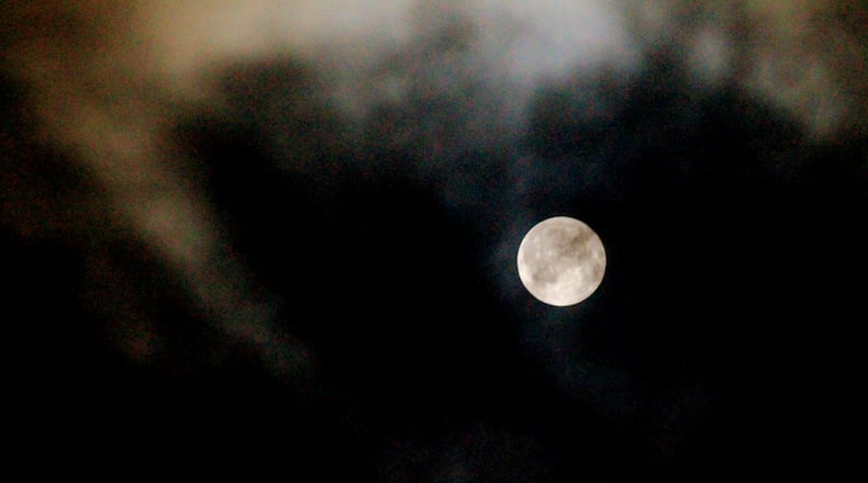 The Harvest Moon, mostly kept hidden by clouds Friday night, finally peeked through night sky in the Farmersville area, Sept. 16, 2016. The moon will be nearly full and visible each night through the weekend. (Jim Noelker/Staff)