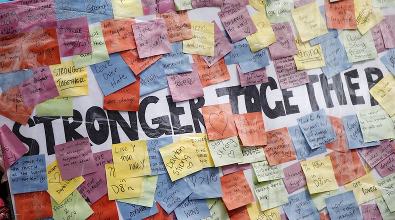 Memorials to victims of the mass shooting on August 4 have begun to shrink in the Oregon District and some business owners would like to have them removed. Many people continued to visit the memorials during the Friday lunch hour.  TY GREENLEES / STAFF