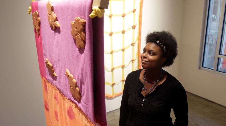 Cydnie King, executive assistant at The Contemporary Dayton look at artworks by artist Britny Wainwright, part of the exhibition, âMatter and Pattern,â on view through March 28. The show is the second in the Still SHE Creates series of exhibitions that highlight women artists pushing boundaries in contemporary art. LISA POWELL / STAFF