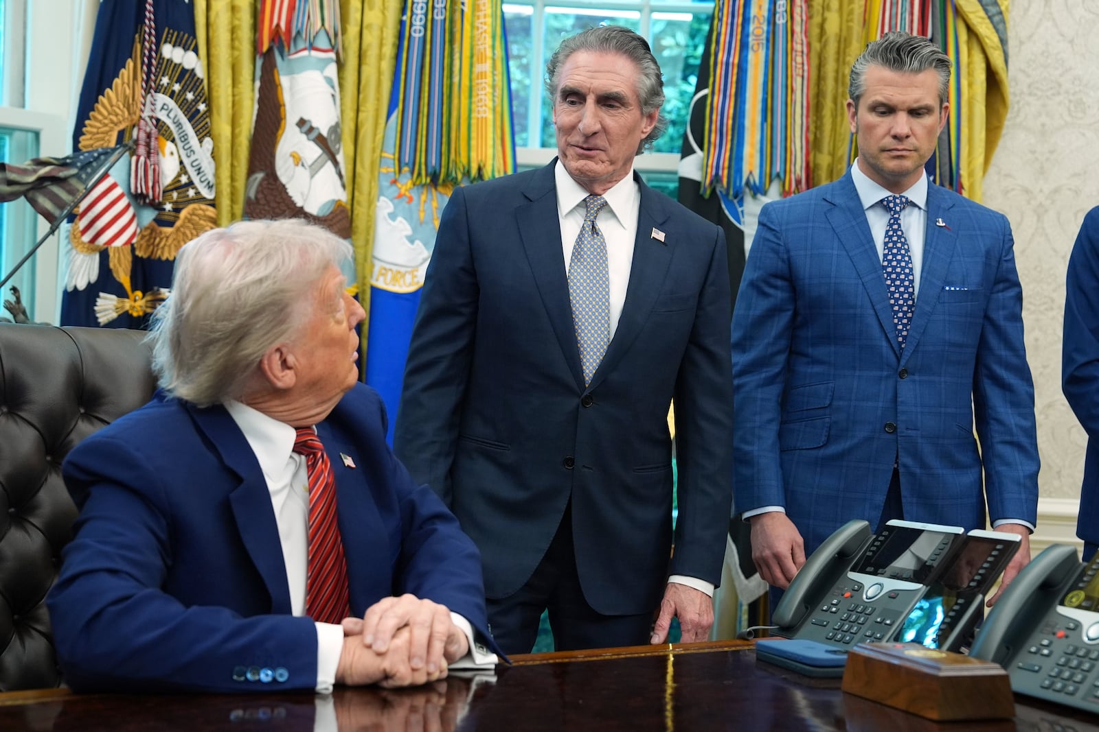 President Donald Trump and Defense Secretary Pete Hegseth listen as Commerce Secretary Howard Lutnick speaks in the Oval Office of the White House, Friday, May 23, 2025, in Washington. (AP Photo/Evan Vucci)