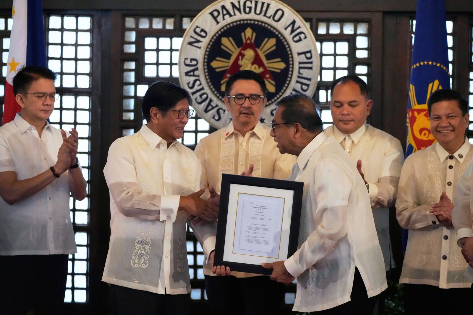 Philippine President Ferdinand Marcos Jr., second from left, congratulates Department of Science and Technology Secretary Renato Solidum Jr. during the presentation of the newly enacted laws to stakeholders at the Malacanang Presidential Palace in Manila, Philippines Thursday, May 22, 2025. (AP Photo/Aaron Favila)