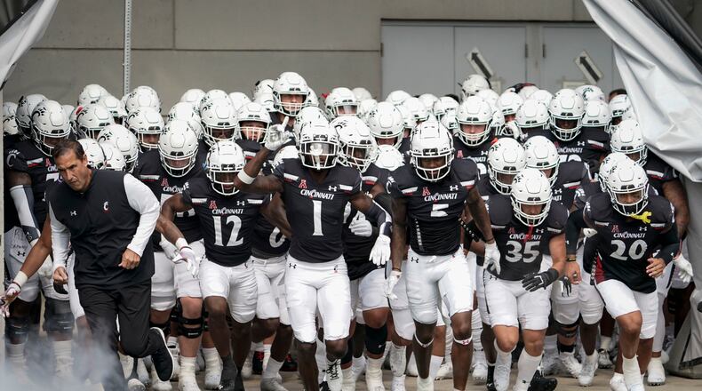 Cincinnati head coach Luke Fickell, left, and Ahmad Gardner (1) lead players onto the field prior to an NCAA college football game against Murray State, Saturday, Sept. 11, 2021, in Cincinnati. (AP Photo/Jeff Dean)