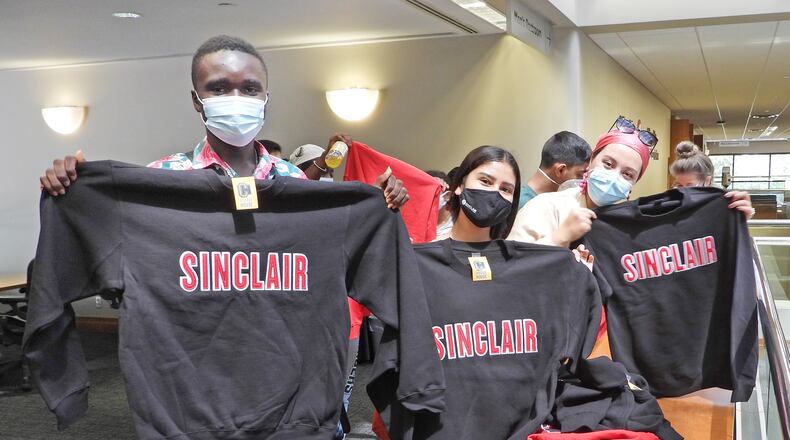 Left to right, Kingsford Ansah of Ghana, Shiwani Khepan from India, and Kerimeay Kucar from Turkey, get Sinclair Community College sweatshirts. Fourteen international students are studying at Sinclair through a State Department program. SUBMITTED