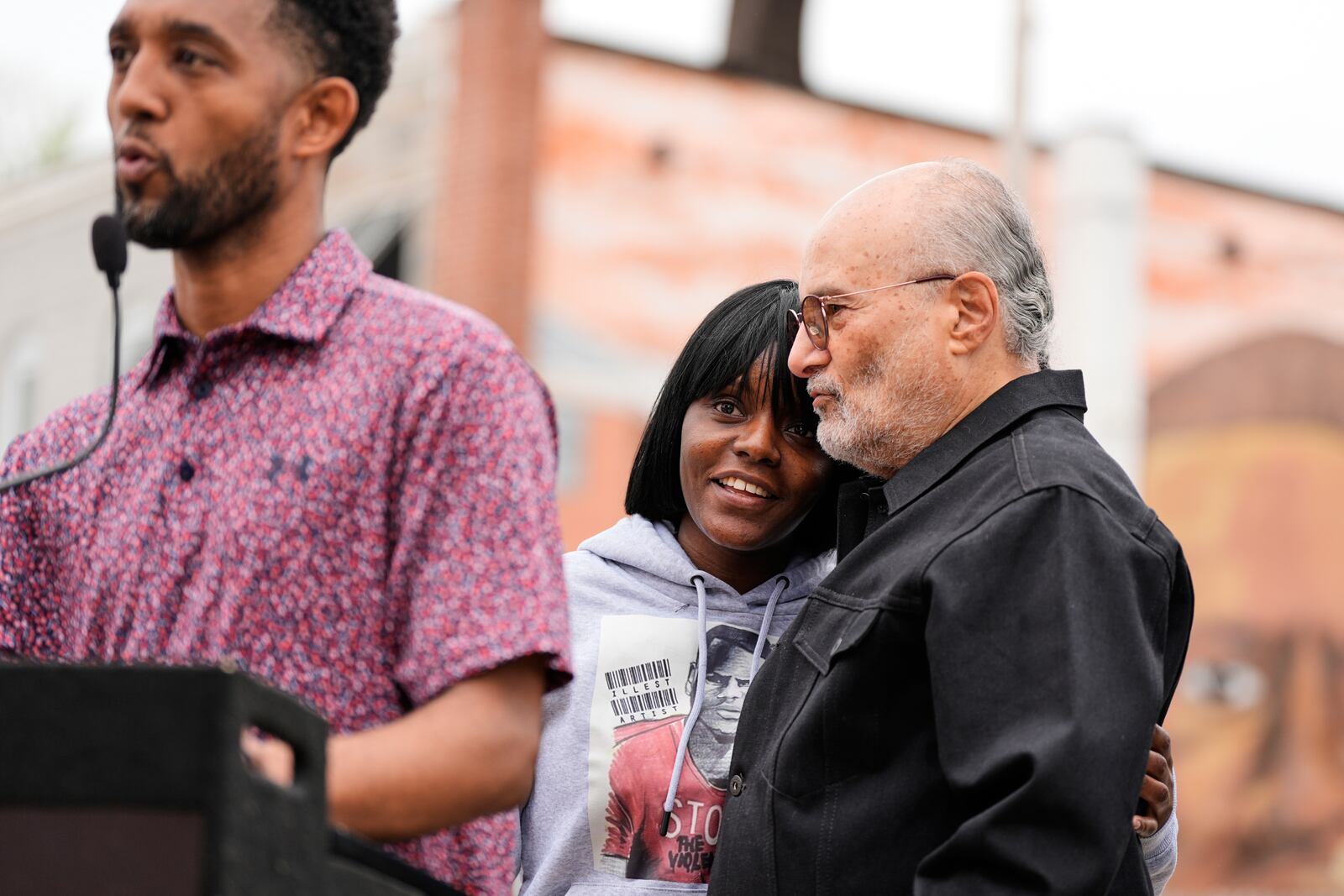Fredricka Gray, twin sister of Freddie Gray, center, embraces William H. "Billy" Murphy, Jr. as Baltimore Mayor Brandon Scott, left, speaks at a memorial event commemorating the ten-year anniversary of the death of Freddie Gray, Saturday, April 19, 2025, in Baltimore. (AP Photo/Stephanie Scarbrough)