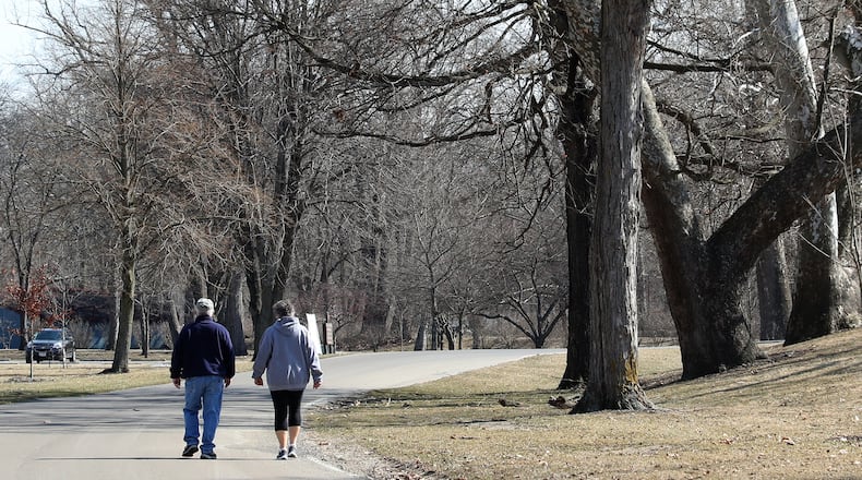 A couple enjoys the warm sunshine as they walks along the roadway in Snyder Park. BILL LACKEY/STAFF