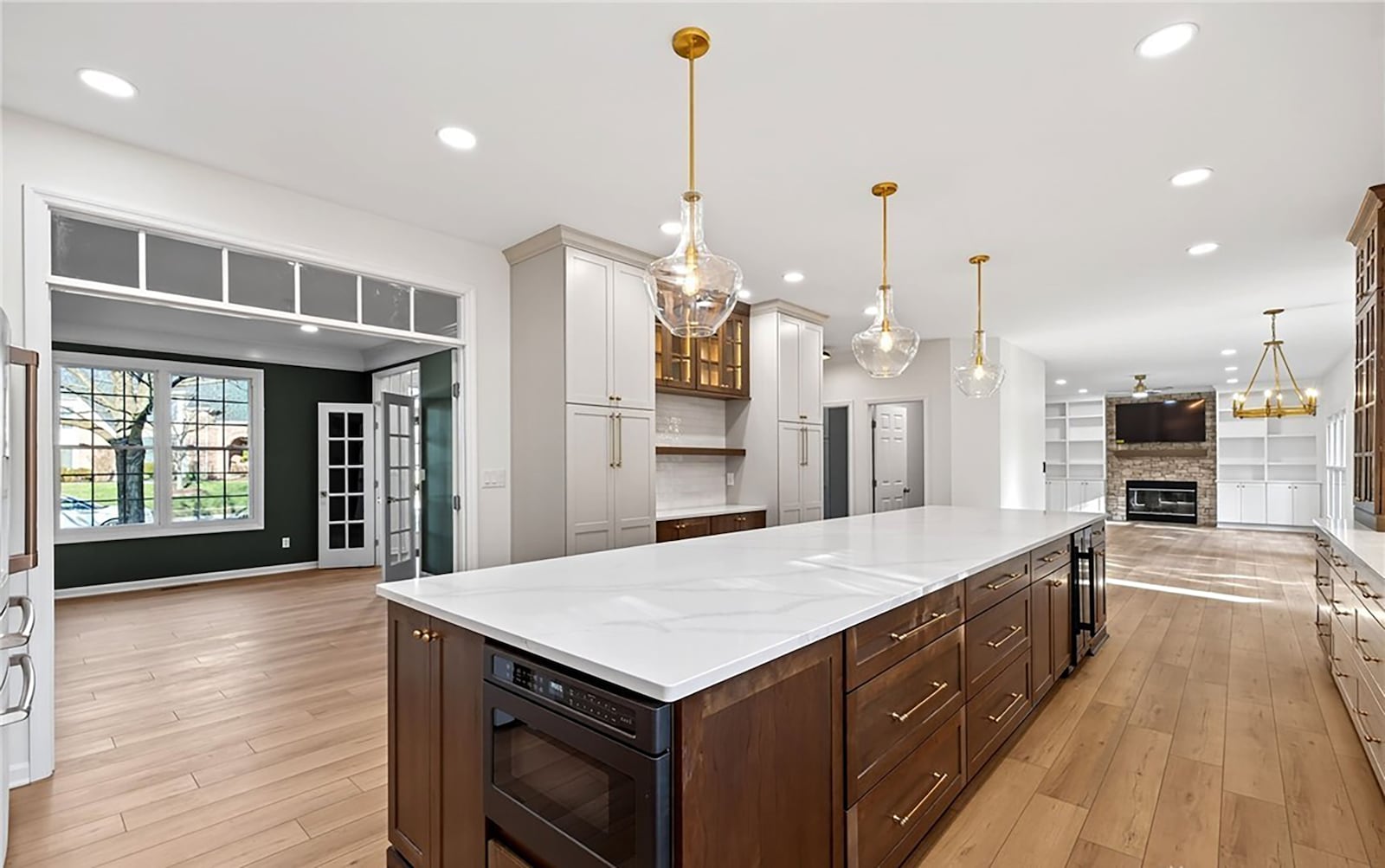 The completely updated kitchen has an island with bar seating, quartz countertops, custom cabinets and a tile backsplash. There is recessed lighting and pendant lighting over the island.  CONTRIBUTED