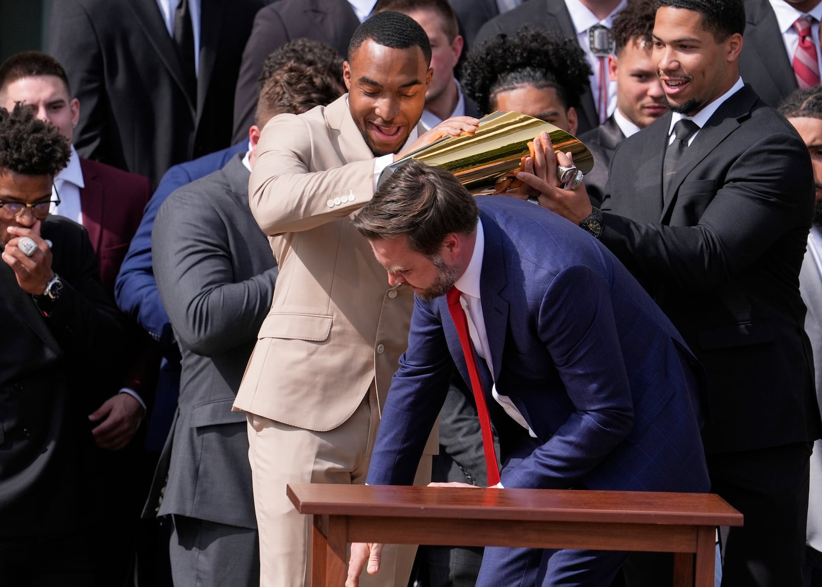 Ohio State University football player TreVeyon Henderson, left, holds the top of the team's championship trophy as Vice President JD Vance reaches to pick up it's base after it fell off, as President Donald Trump welcomes the 2025 College Football National Champions during an event on the South Lawn of the White House, Monday, April 14, 2025, in Washington. (AP Photo/Manuel Balce Ceneta)