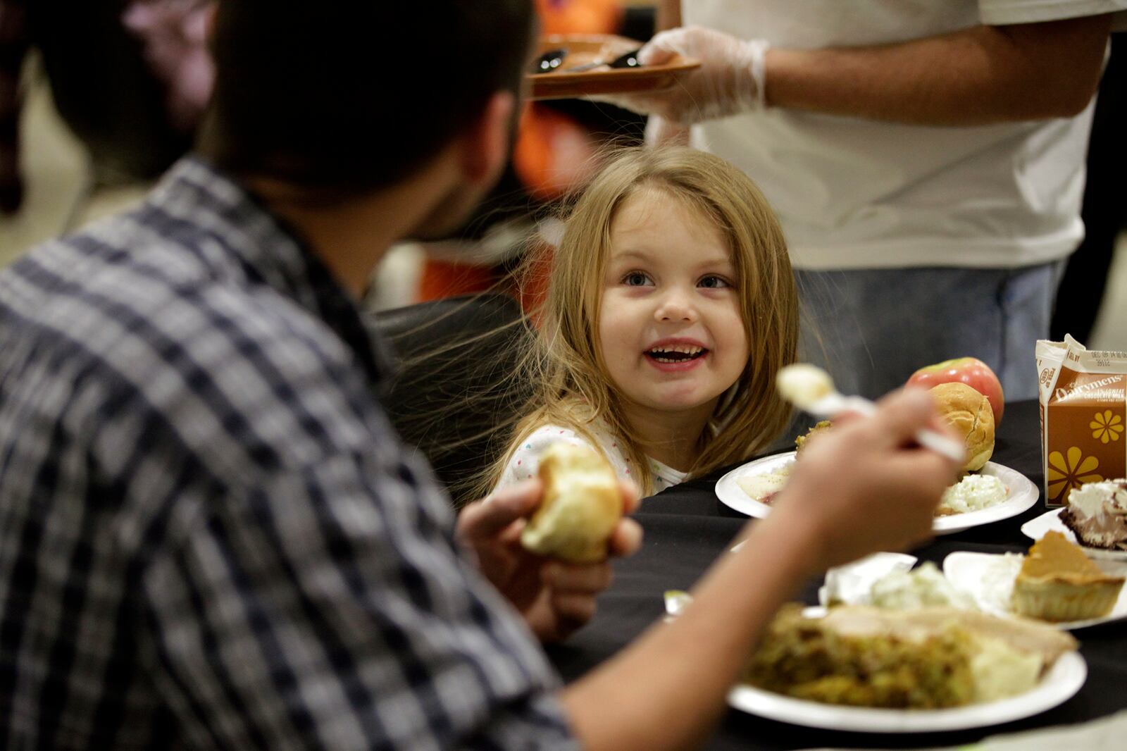 Faith Marie Oakes, 4, enjoys dinner with her father Eric Anders of Dayton during the Feast of Giving, an annual event held each Thanksgiving Day at the Dayton Convention Center. LISA POWELL / STAFF PHOTO