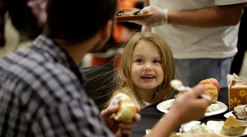 Faith Marie Oakes, 4, enjoys dinner with her father Eric Anders of Dayton during the Feast of Giving, an annual event held each Thanksgiving Day at the Dayton Convention Center. LISA POWELL / STAFF PHOTO
