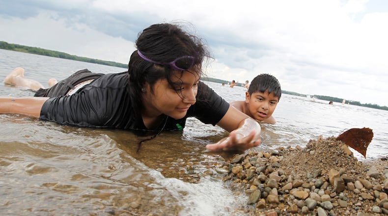 Perla Manzano, 14, and her brother, Juan, 9, pile up rocks along the shore line as they play in the water at the Buck Creek State Park beach Monday, June 19, 2017. Bill Lackey/Staff