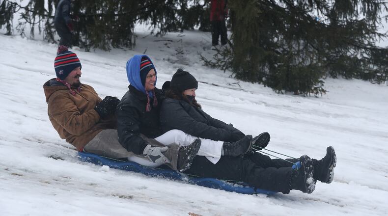A group of adults join in the fun as they take a turn sledding down a snow covered hill on the Wittenberg University campus Sunday. BILL LACKEY/STAFF