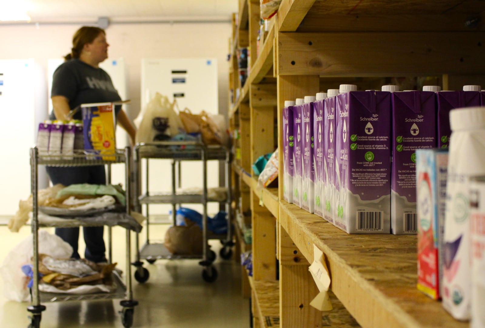 A volunteer at Belmont Church's pantry restocks shelves after dozens of local people shopped around the pantry. STAFF/SYDNEY DAWES