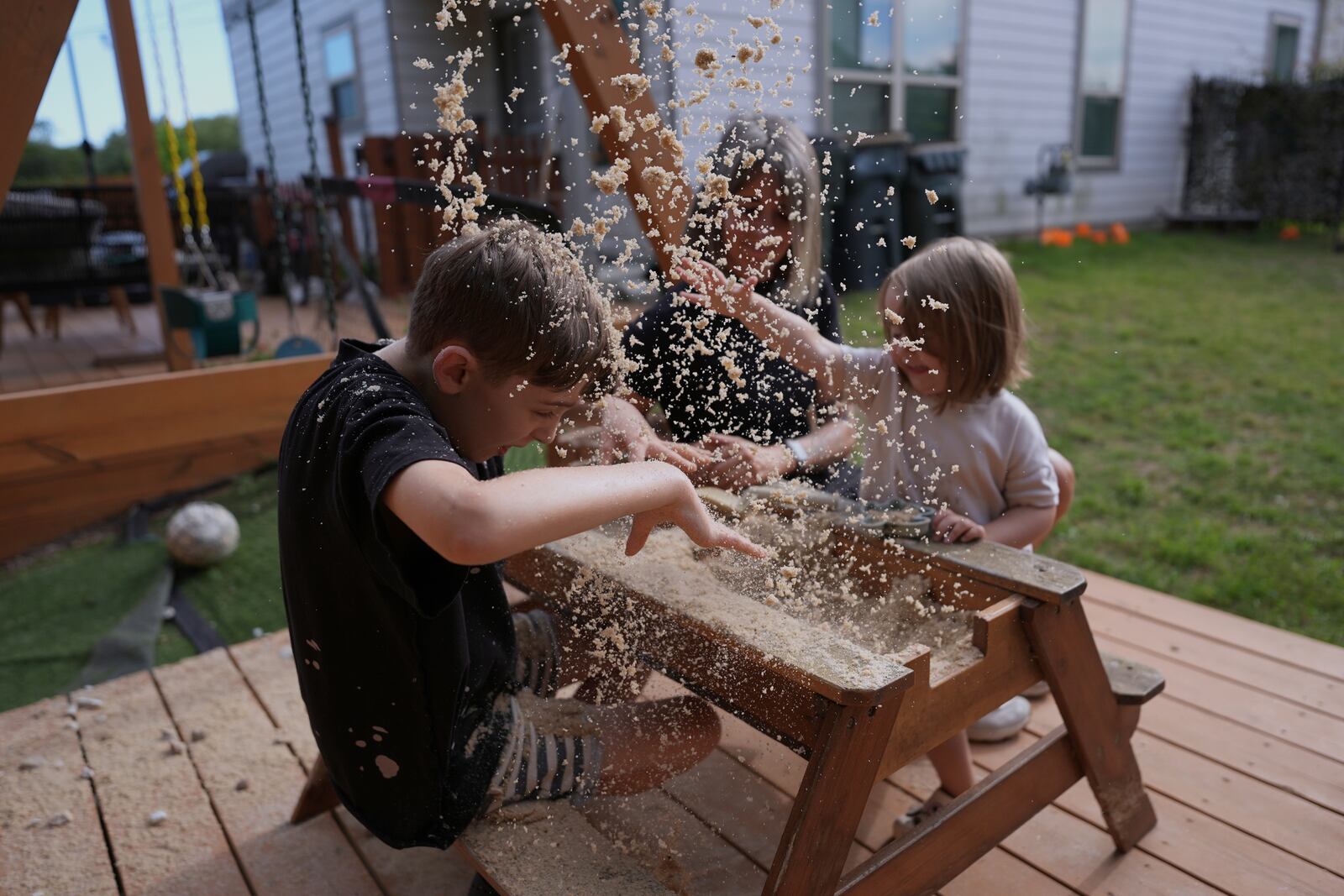 Eileen Lamb, center, who was diagnosed with autism as an adult, works with her son Charlie Lamb, left, who also has autism, and daughter Billie at their home, Monday, May 12, 2025, in Austin, Texas. (AP Photo/Eric Gay)