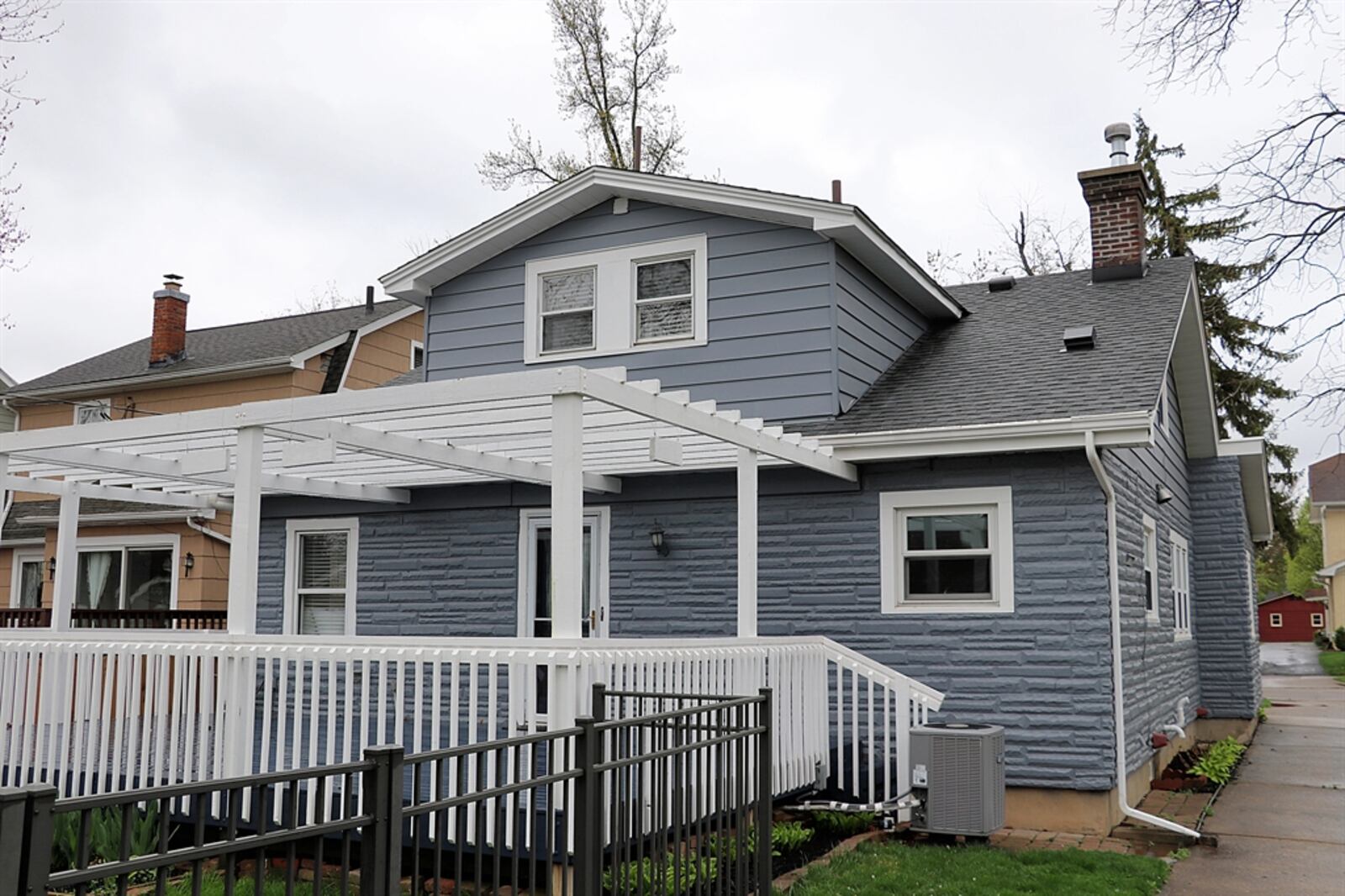 The backyard is fenced and a large wooden deck has been painted to match the home and has a pergola covering.