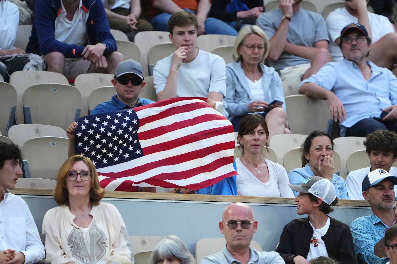 A spectator holds a flag of the United States as he watches the fourth round match of the French Tennis Open between Germany's Daniel Altmaier and Frances Tiafoe of the United States, at the Roland-Garros stadium, in Paris, Sunday, June 1 2025. (AP Photo/Lindsey Wasson)