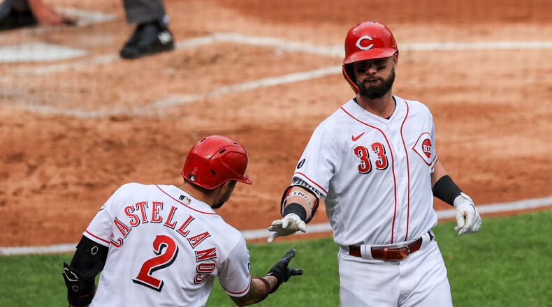 Cincinnati Reds' Jesse Winker (33) is greeted by Nick Castellanos after hitting a solo home run during the third inning of a baseball game against the Milwaukee Brewers in Cincinnati, Saturday, May 22, 2021. (AP Photo/Aaron Doster)