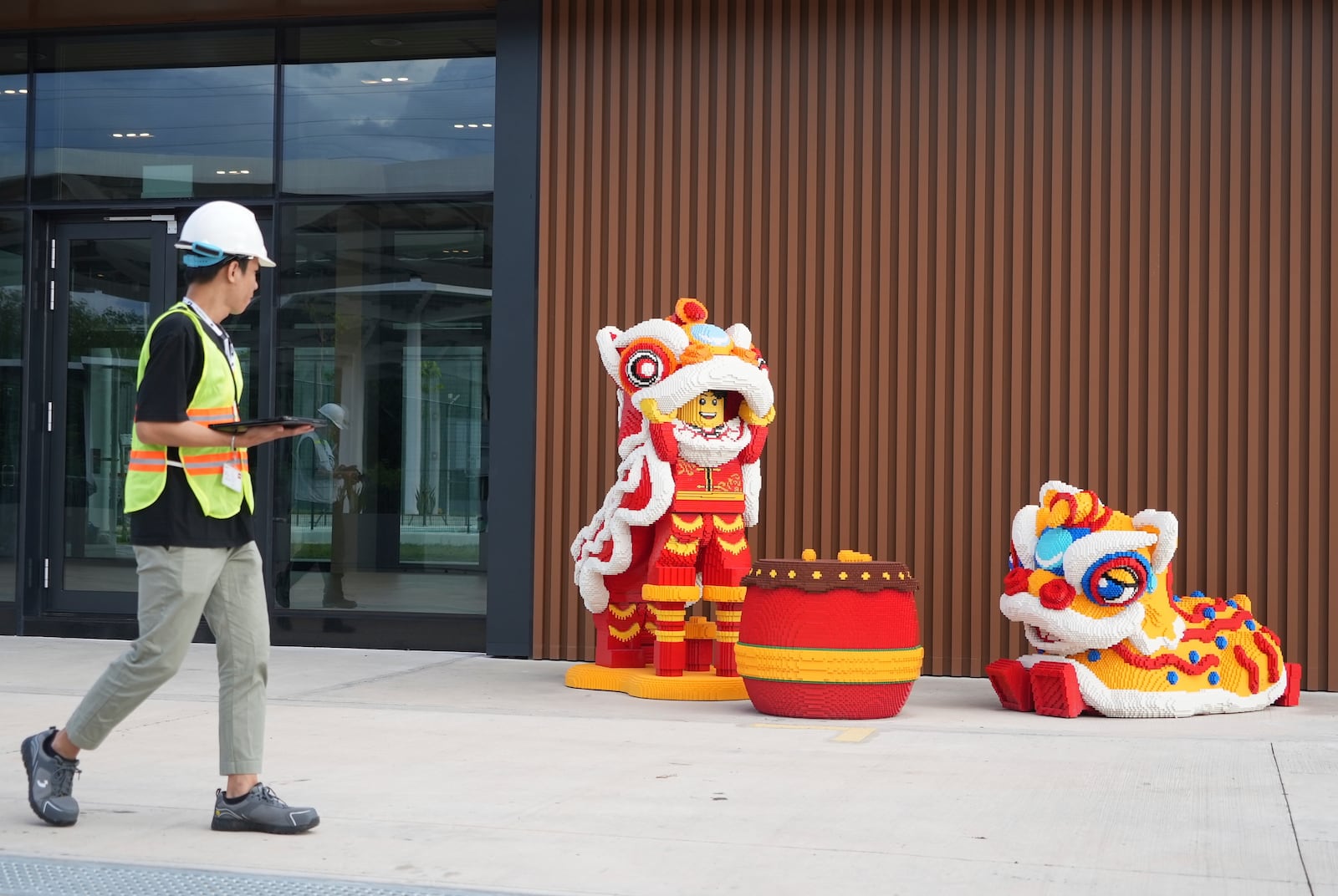 A worker walks past Lego characters in Vietnamese traditional lion dance costumes displayed at Lego factory in Binh Duong, Vietnam Wednesday, April 2, 2025. (AP Photo/Hau Dinh)