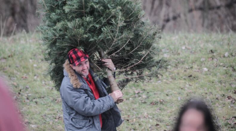 Sean Crowe, from Kettering, drops off his tree at Eastwood Metro Park. JIM NOELKER/STAFF