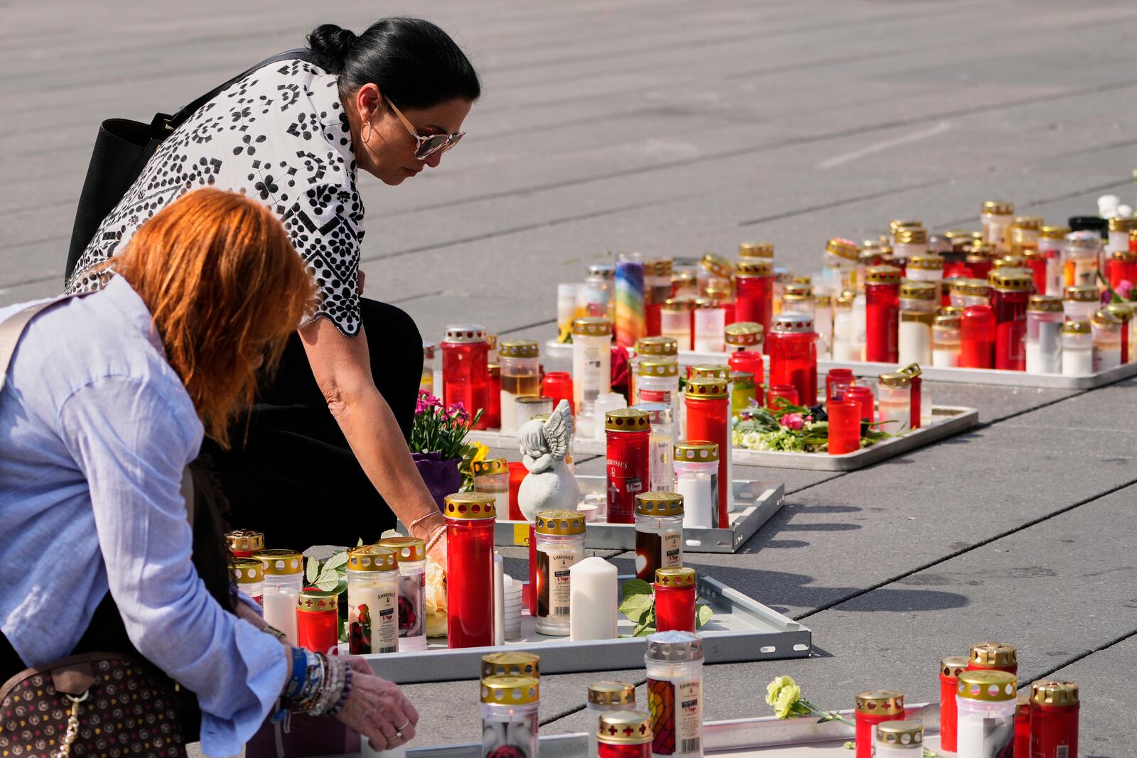 People light candles on the main square after a former student opened fire the day before at a school fatally wounding several people and injuring many others before taking his own life, Graz, Austria, Wednesday, June 11, 2025. (AP Photo/Darko Bandic)