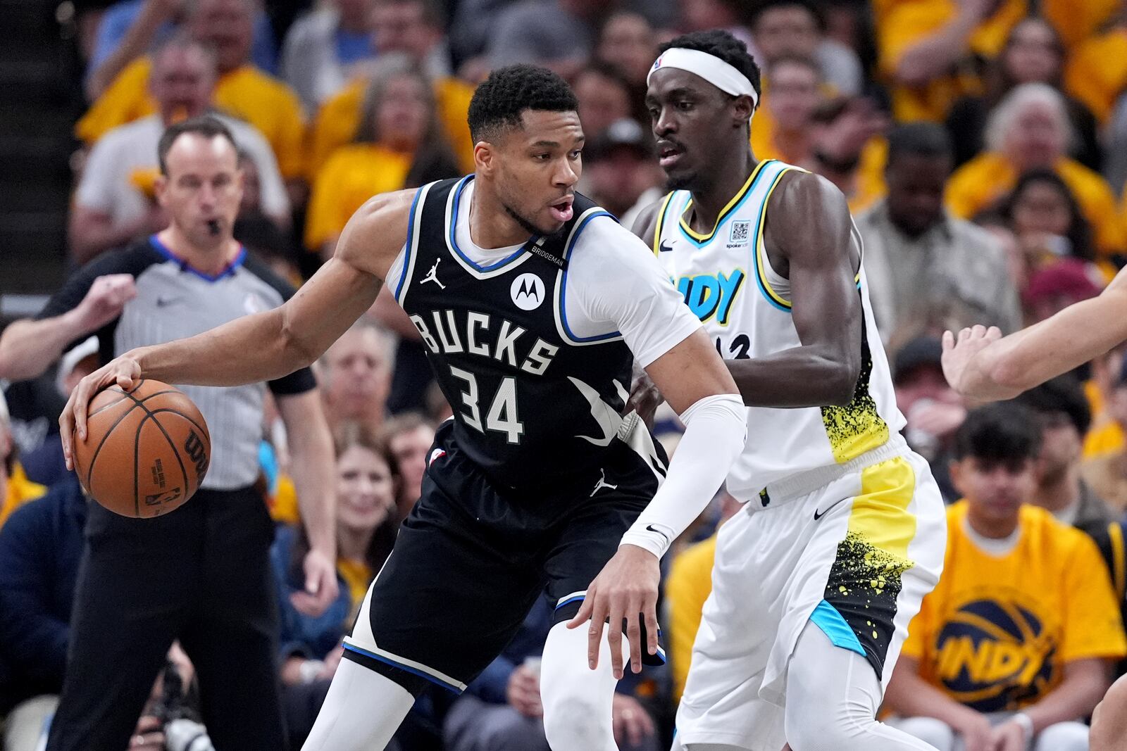 Milwaukee Bucks' Giannis Antetokounmpo (34) dribbles as Indiana Pacers' Pascal Siakam defends during the first half of a first-round NBA basketball playoff game, Saturday, April 19, 2025, in Indianapolis. (AP Photo/Michael Conroy)