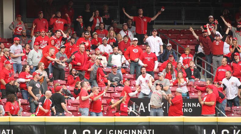 Fans try to catch a home run hit by the Reds' Scooter Gennett in the ninth inning against the Phillies on Monday, April 3, 2017, at Great American Ball Park in Cincinnati.