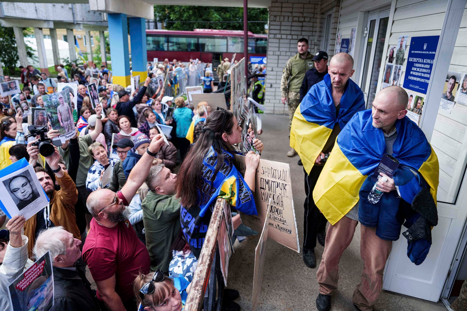 Ukrainian soldiers walk in front of a crowd of people holding photos of their missed relatives after returning from captivity after a POWs exchange between Russia and Ukraine, in Chernyhiv region, Ukraine, Thursday, June 26, 2025. (AP Photo/Evgeniy Maloletka)