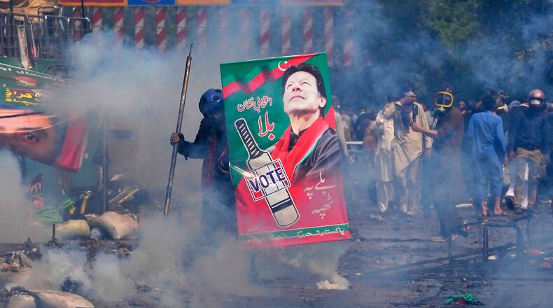 FILE - Supporters of former Prime Minister Imran Khan take cover after riot police officers fire tear gas to disperse them during clashes, in Lahore, Pakistan, Wednesday, March 15, 2023. (AP Photo/K.M. Chaudary, File)