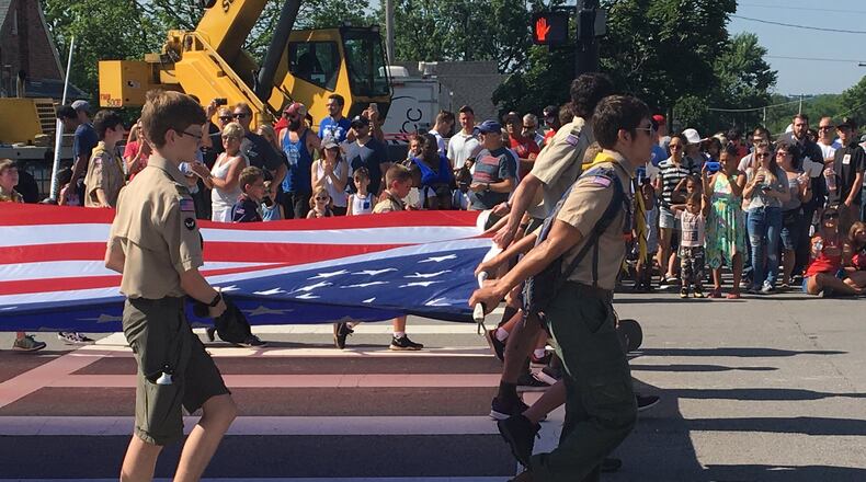 A troop of boy scouts carry an American flag in the parade at the 45th Americana Festival in Centerville on Wednesday. The annual festival drew thousands of visitors despite high temperatures.