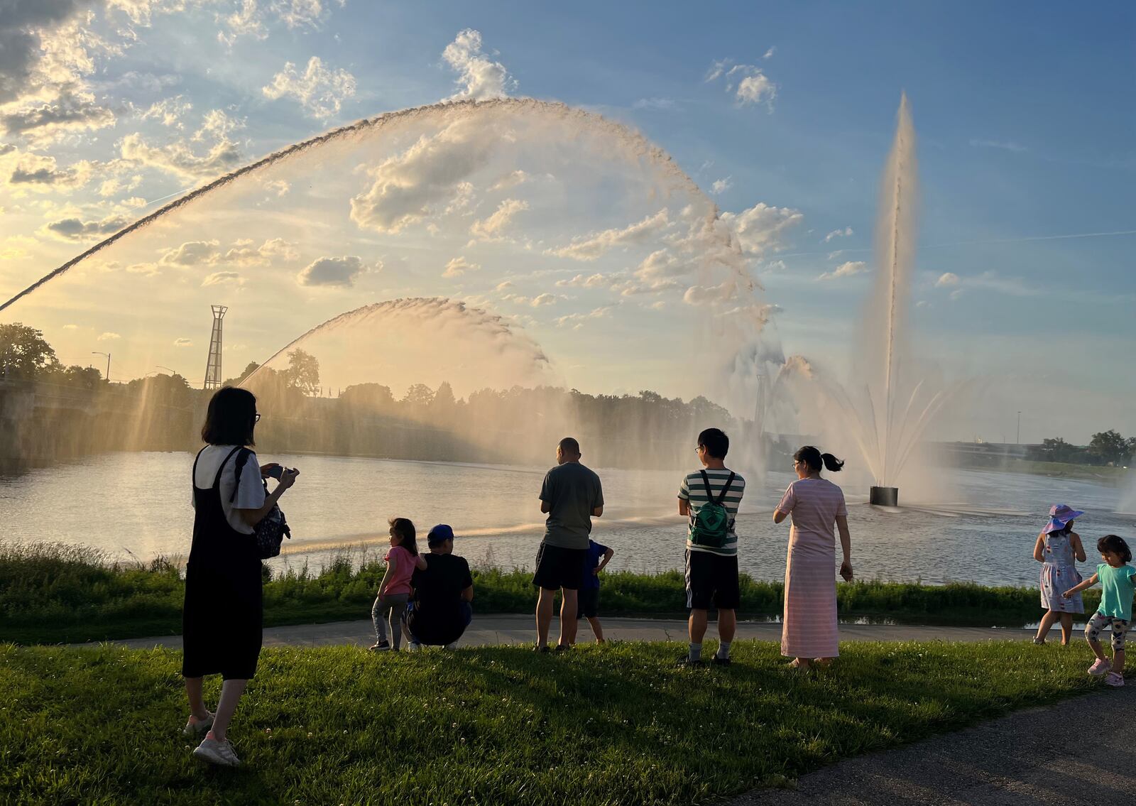 On Monday evening, community members gathered along the banks of the Mad River to watch the Five Rivers Fountains of Light, which after a winter hibernation were turned on over Memorial Day weekend. The five fountains at the confluence of the Great Miami and Mad River shoot water about 200 feet high and 400 feet across. The fountains at RiverScape were installed in 2001. CORNELIUS FROLIK / STAFF 