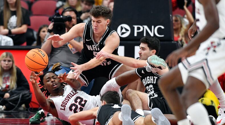 Louisville forward Kamari Lands (22) tosses a loose ball to a teammate away from Wright State forward Blake Sisley (52) and guard Andrew Welage (22) during the first half of an NCAA college basketball game in Louisville, Ky., Saturday, Nov. 12, 2022. (AP Photo/Timothy D. Easley)