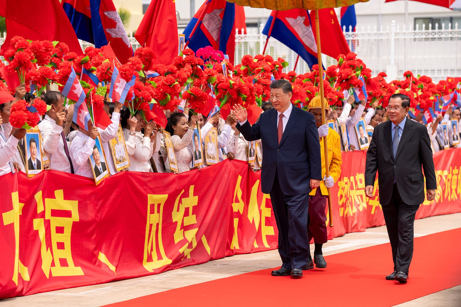 In this photo released by Agence Kampuchea Press (AKP), Chinese President Xi Jingping, left on the carpet, greets the crowd as he is accompanied by Cambodian Senate President Hun Sen, right, during a send-off ceremony at Phnom Penh International Airport in Phnom Penh, Cambodia, Friday, April 18, 2025. (AKP via AP)