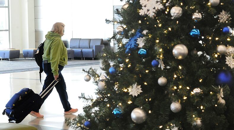 A lone traveler makes her way through the Dayton International Airport Monday, Dec. 20, 2021 United and Delta announced Thursday that they have canceled hundreds of flights, largely due to staffing shortages created by the spread of COVID-19. MARSHALL GORBY\STAFF