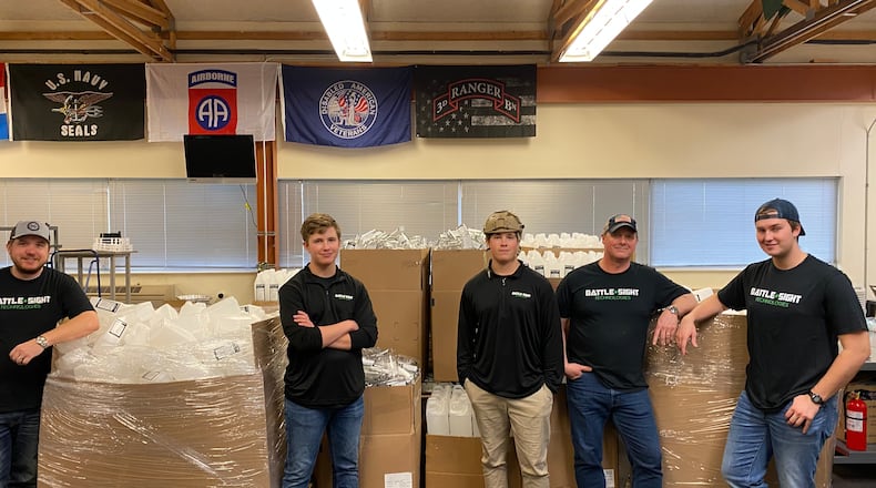 Battle Sight Technologies workers with boxes of newly produced hand sanitizer ready for the front lines. CONTRIBUTED