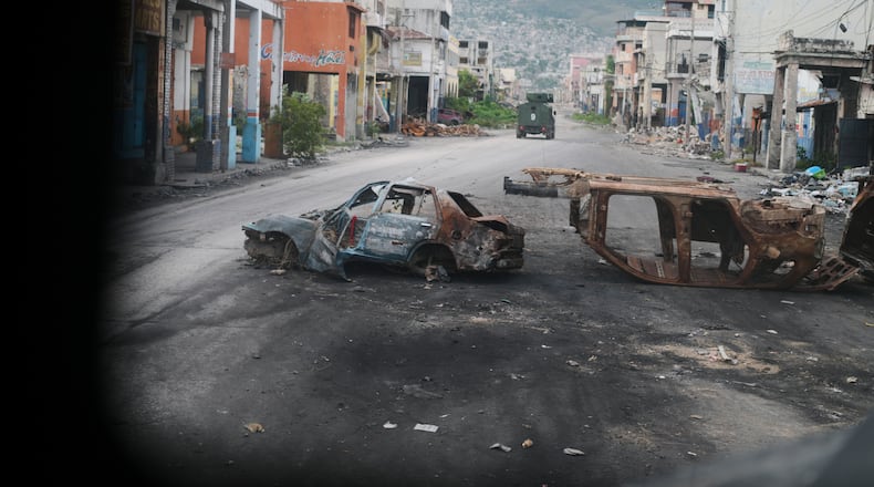 Burned cars block a street, photographed from inside an armored police vehicle patrolling a gang-controlled area in Port-au-Prince, Haiti, Friday, Jan. 16, 2026. (AP Photo/Odelyn Joseph)