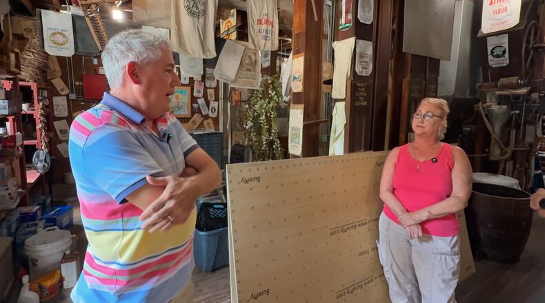 Councilmembers Anthony Satariano and Paula Lazorski stand inside the Historic Clifton Mill, surrounded by flour sack displays and mill equipment.