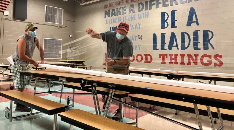 Custodians Mark Daniels and Mitch Gearhardt place plexiglass on tables at Driscoll Elementary in the Centerville school district.